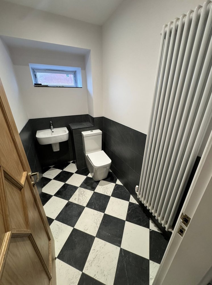 Cloakroom with black and white chequered floor and a tall white column radiator