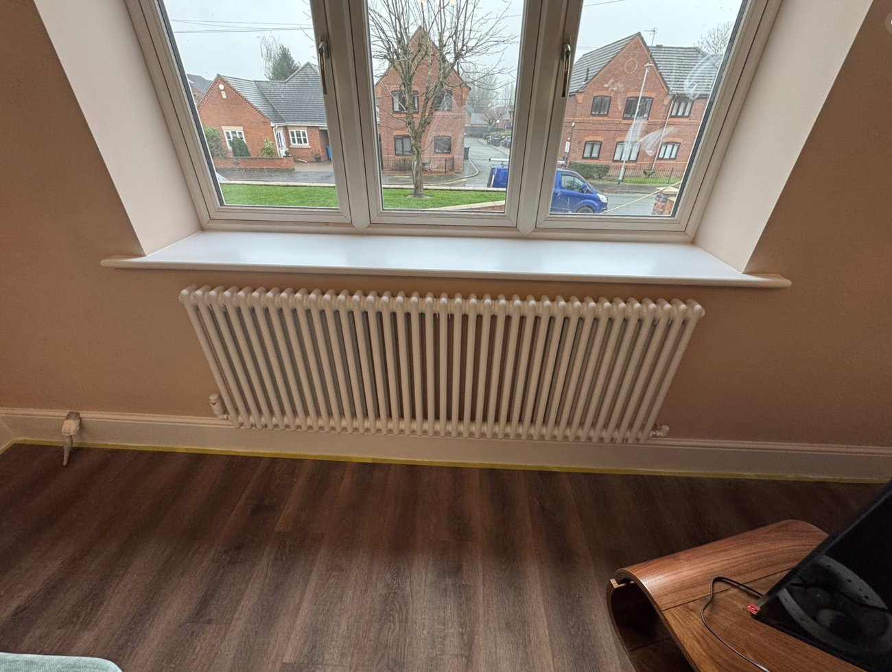 A white column radiator fitted under a living room window