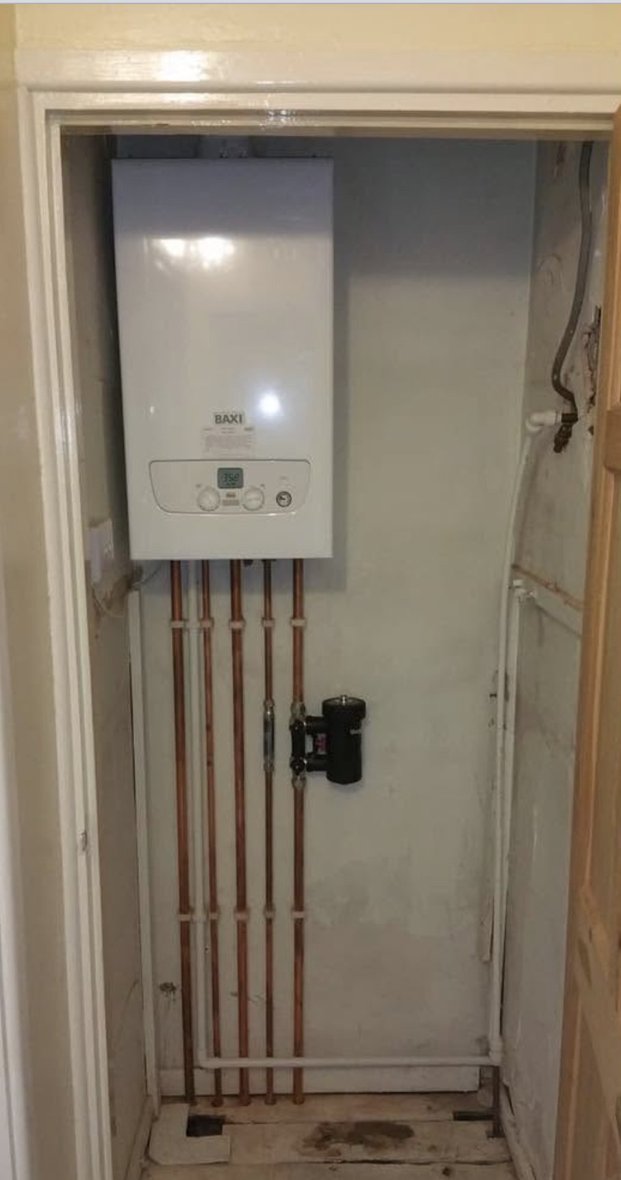 A new Baxi boiler with neat copper pipework in a cupboard