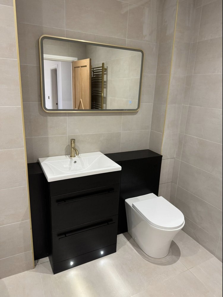 Black vanity unit with brushed gold tap and gold-framed mirror